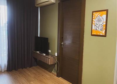 Compact bedroom with wooden flooring, air conditioning unit, and television