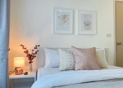 Cozy bedroom with neatly arranged bed, decorative pillows, and wall art