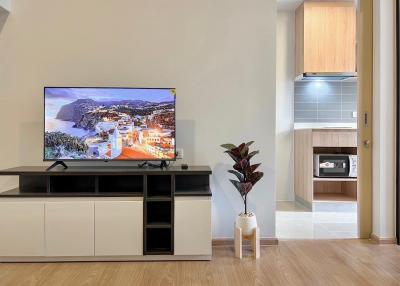 Modern living room interior with mounted television and adjacent kitchenette