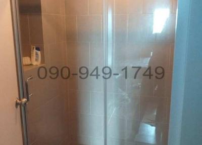 Glass-enclosed shower area in bathroom with tiled walls