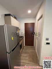 Narrow corridor with modern fridge, wooden door, and tiled flooring