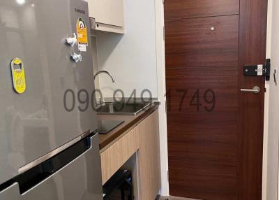 Compact modern kitchen with stainless steel refrigerator and wooden cabinets