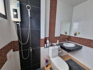 Modern bathroom with black and mosaic tiles, shower, and white fixtures