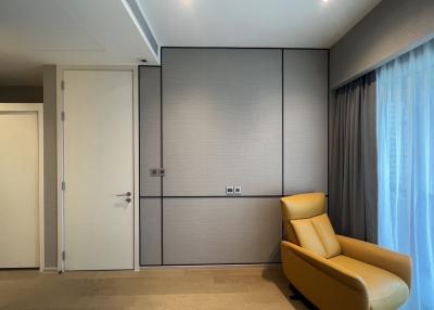 Minimalistic bedroom with a modern yellow armchair, large window with curtains, and built-in wardrobe