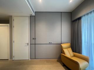 Minimalistic bedroom with a modern yellow armchair, large window with curtains, and built-in wardrobe