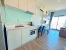 Modern apartment kitchen with dining area leading to a well-lit living room with balcony access