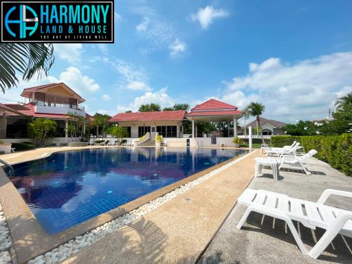 Spacious outdoor area with swimming pool and loungers under clear blue sky