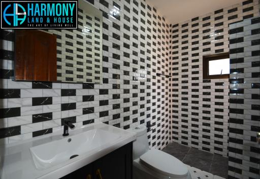 Modern bathroom with black and white tiled walls, large mirror, and wooden cabinet