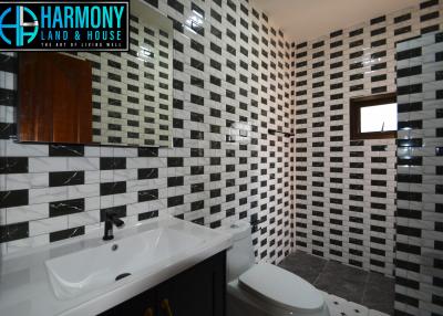 Modern bathroom with black and white tiled walls, large mirror, and wooden cabinet