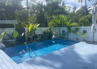 Private swimming pool surrounded by lush greenery and a spacious deck