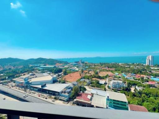 Panoramic view from a high-rise balcony overlooking a coastal city with blue skies