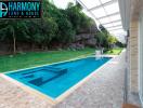 Modern outdoor swimming pool with transparent roofing next to a house