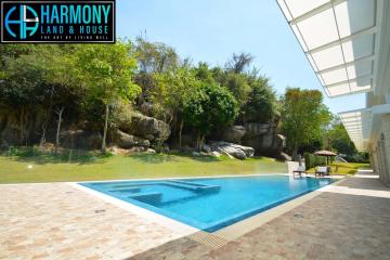 Luxurious outdoor swimming pool with natural rock formation and lush landscaping