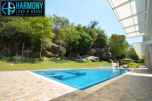Luxurious outdoor swimming pool with natural rock formation and lush landscaping