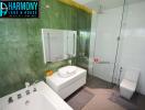 Modern bathroom with green marble walls, a large mirror, and white fixtures