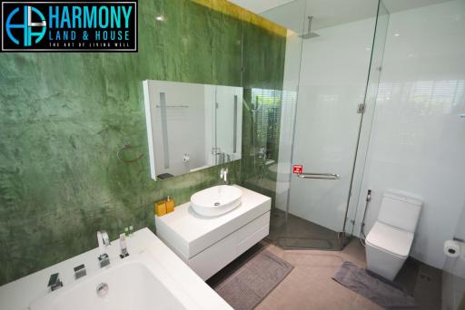 Modern bathroom with green marble walls, a large mirror, and white fixtures