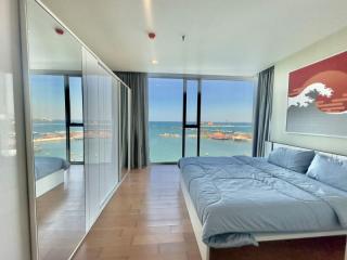 Modern bedroom with ocean view through floor-to-ceiling windows