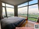Modern bedroom with large windows offering a panoramic city view