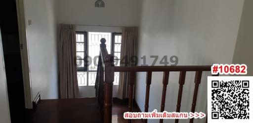 Spacious upper-level hallway with wooden banister and large windows