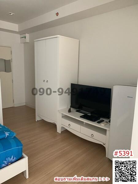 Compact bedroom with white wardrobe and mounted TV