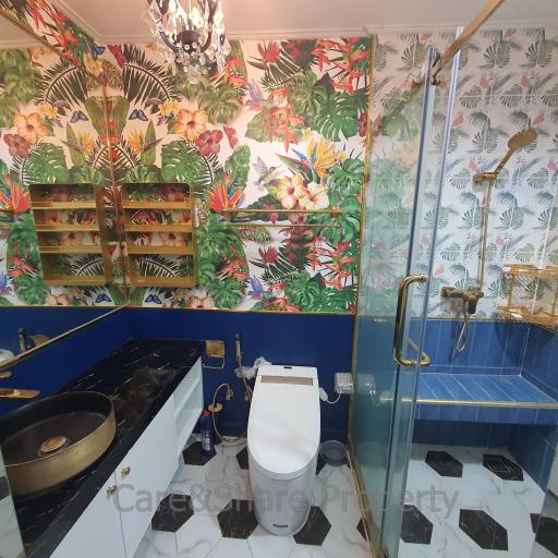 Colorful tropical-themed bathroom with a walk-in shower and artistic wallpaper