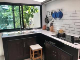 Modern kitchen with garden view, featuring stainless steel appliances and dark cabinetry