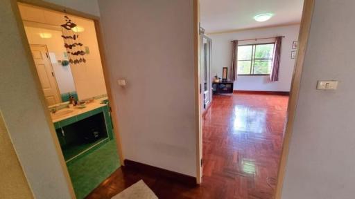 Interior view of a house showing the entrance hall leading to a spacious living room with hardwood floors