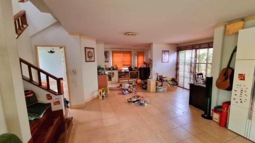 Spacious living area with kitchen in the background and staircase to the side