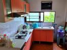 Bright kitchen with orange cabinetry and tiled backsplash