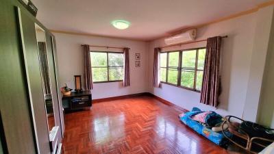 Spacious bedroom with glossy hardwood floor and natural light