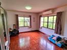 Spacious bedroom with glossy hardwood floor and natural light