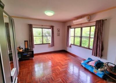 Spacious bedroom with glossy hardwood floor and natural light