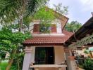 Traditional house with red roof surrounded by greenery