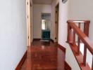 Warmly lit hallway with polished wooden stairs and flooring leading towards rooms