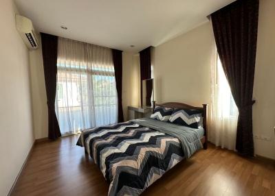Cozy bedroom with wooden flooring, ample natural light, and comfortable bedding