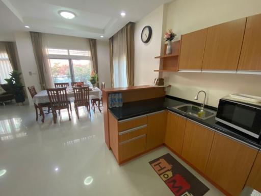 Modern kitchen with wooden cabinets and integrated appliances adjacent to dining area