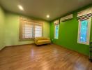 Spacious bedroom with green walls and hardwood flooring