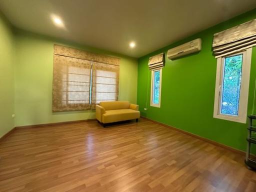 Spacious bedroom with green walls and hardwood flooring