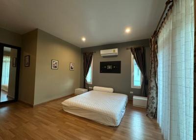 Spacious bedroom with hardwood floors and modern air conditioning