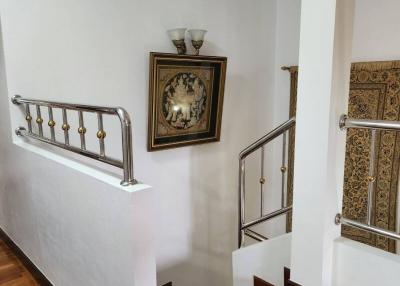 Elegant staircase with wooden floors, decorative railing, and wall art