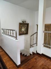 Elegant staircase with wooden floors, decorative railing, and wall art