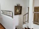 Elegant staircase with wooden floors, decorative railing, and wall art