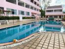 Swimming pool with blue water in front of a pink residential building