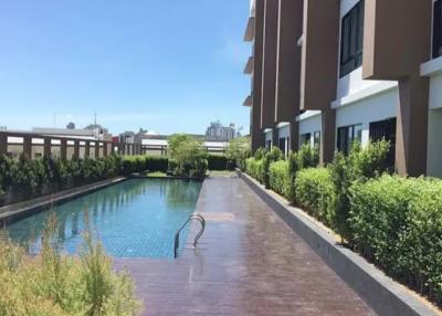 Outdoor swimming pool alongside residential building with sunny blue sky