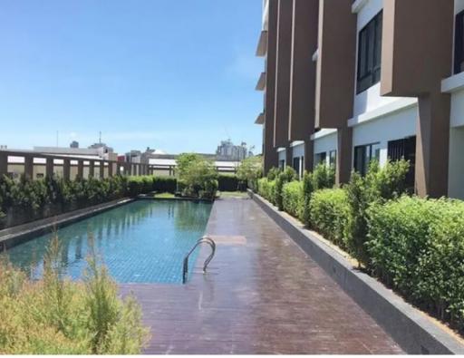 Outdoor swimming pool alongside residential building with sunny blue sky