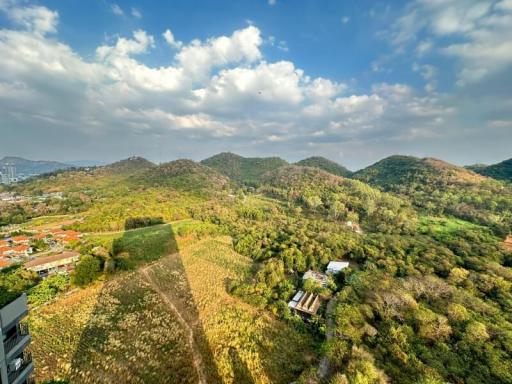 Aerial view of a lush landscape with mountains, trees, and clear skies