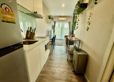 Modern kitchen with white cabinetry and wooden floors leading to a dining area