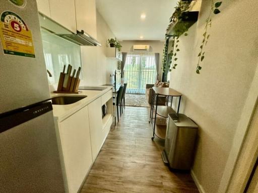 Modern kitchen with white cabinetry and wooden floors leading to a dining area