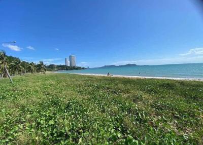 Scenic beachfront view with clear skies and high-rise building in the distance