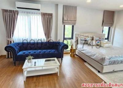 Spacious combined bedroom and living area with elegant sofa and large bed